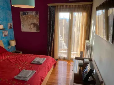 a bedroom with a red bed and a window at In the heart of Athens! Panoramic view of the Acropolis! in Athens