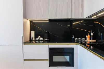 a kitchen with white cabinets and a black oven at N K Suite - Design Boutique Stay with City view in Athens
