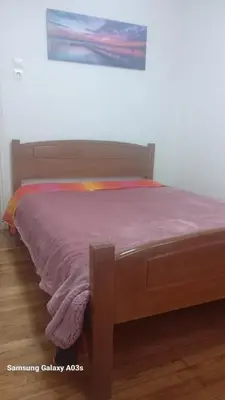 a bed with a wooden frame in a room at George's home in Piraeus