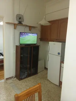 a kitchen with a tv on a cabinet with a refrigerator at George's home in Piraeus
