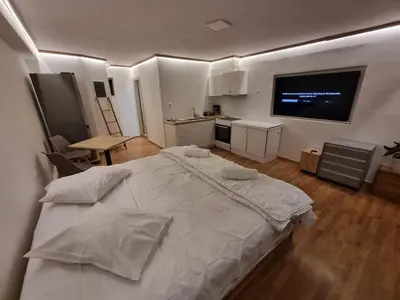 a bedroom with a large white bed and a kitchen at Loft apartment by the sea in Athens
