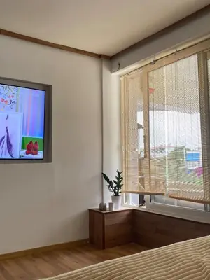 a bedroom with a large window and a television at Loft apartment by the sea in Athens