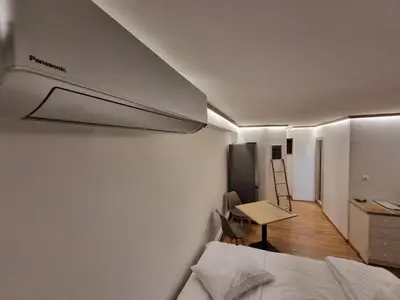 a bedroom with a bed and a desk and a kitchen at Loft apartment by the sea in Athens