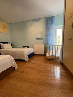 a bedroom with two beds and a window and wooden floors at Summer villa Levon in Lagonissi