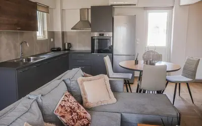 a living room with a couch and a kitchen with a table at Athenean Coastal Getaway in Athens