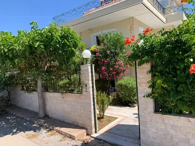 a house with trees and flowers in front of it at 1 Bed Apartment near the beach in Aghia Marina