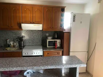 a kitchen with wooden cabinets and a white refrigerator at 1 Bed Apartment near the beach in Aghia Marina