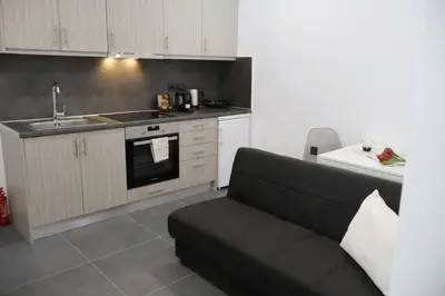 a living room with a couch and a kitchen at Athenean Porto Piraeus Suites -GF1 in Piraeus