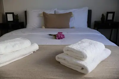 a bed with white towels and a pink flower on it at Athenean Porto Piraeus Suites -A1 in Piraeus