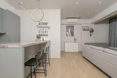 a living room with a couch and a bar with stools at Minimal Style Apartment in Piraeus