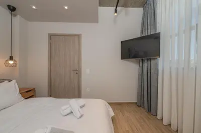 a bedroom with a white bed with a flat screen tv at Minimal Style Apartment in Piraeus