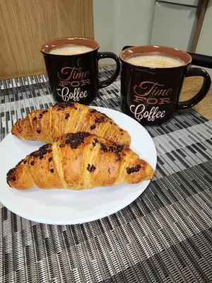 two pastries on a plate next to two cups of coffee at Kallithea VIP Apartments in Athens