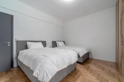 two beds in a bedroom with white walls and wooden floors at Urban Nest 1 in Athens