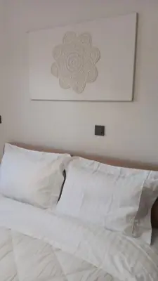 a white bed with white pillows and a picture on the wall at Adorable apartment in Athens