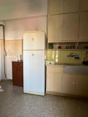 a white refrigerator in a kitchen with wooden cabinets at The Kallimarmaro Nest in Athens