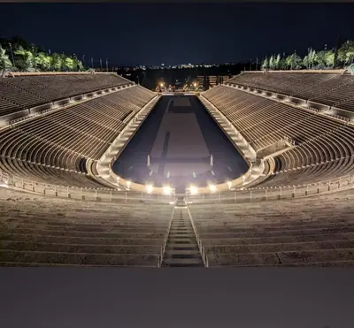 an empty amphitheater at night with lights at The Kallimarmaro Nest in Athens