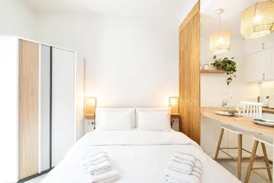 a white bedroom with a bed and a kitchen at Central Modern Studio with balcony,1 min to Metro,10 min to Acropolis in Athens