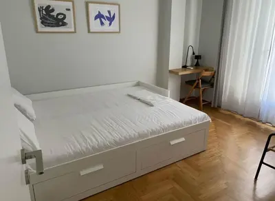 a white bed in a room with a wooden floor at Iris 2 Bedroom with Balcony in Pagkrati in Athens