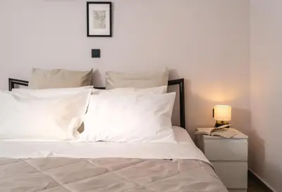 a white bed with white pillows and a lamp on a night stand at Athens Neos Kosmos 1BDR apt near to metro station in Athens