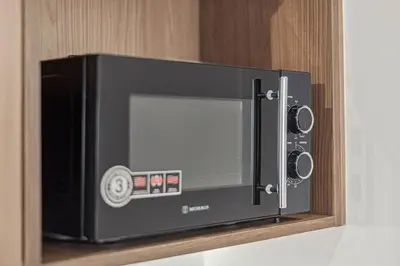 a black microwave oven sitting on a shelf at The Athens Luminous Suite in Athens