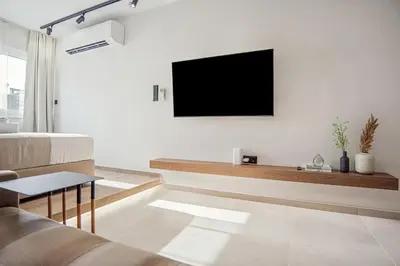 a living room with a couch and a tv on a wall at The Athens Luminous Suite in Athens