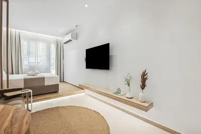 a white room with a bed and a tv on a wall at The Athens Edit Suite in Athens