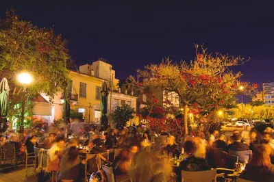 a crowd of people sitting at tables on a street at night at Panormou Urban Getaway Next to Metro Fast Wi-Fi in Athens