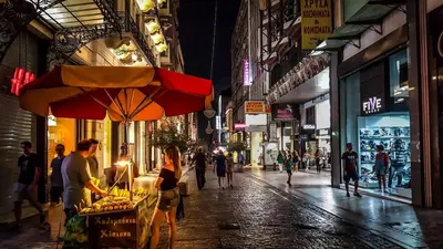 a woman standing next to a food stand on a street at night at Panormou Urban Getaway Next to Metro Fast Wi-Fi in Athens