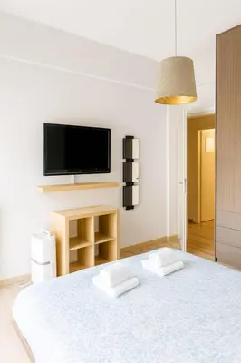 a white room with a bed and a tv on the wall at Panormou Urban Getaway Next to Metro Fast Wi-Fi in Athens