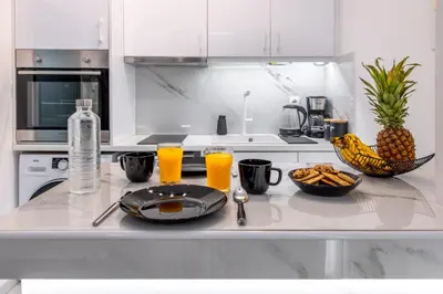 a kitchen counter with a plate of food and two glasses of orange juice at Aqua Bliss Piraeus in Piraeus