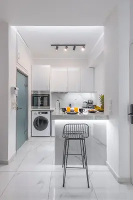 a white kitchen with a stool and a counter at Aqua Bliss Piraeus in Piraeus