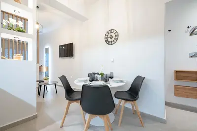 a dining room with a table and chairs and a clock at Piraeus Deluxe by the sea in Piraeus