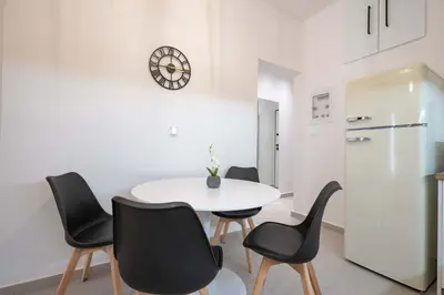 a dining room with a white table and black chairs at Piraeus Deluxe by the sea in Piraeus