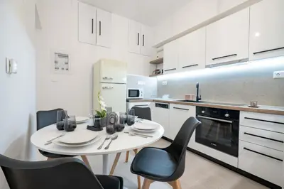 a white kitchen with a white table and chairs at Piraeus Deluxe by the sea in Piraeus