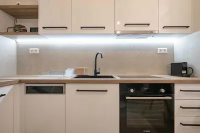 a kitchen with white cabinets and a sink and a stove at Piraeus Deluxe by the sea in Piraeus