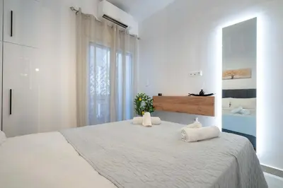 a white bedroom with a large bed with two pillows at Piraeus Deluxe by the sea in Piraeus