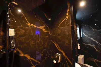 a bathroom with a marble wall with a toilet and lights at Comfort Room 217 - Castle De Paris in Athens