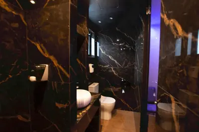 a bathroom with a toilet and a black marble wall at Comfort Room 217 - Castle De Paris in Athens