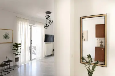 a white living room with a mirror on the wall at Elegant Apartment in Glyfada A1 in Athens