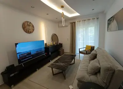 a living room with a couch and a flat screen tv at Coastal Elegance 1-Bedroom Hideaway by the Beach in Athens