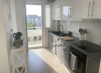 a kitchen with white cabinets and a black counter top at Coastal Elegance 1-Bedroom Hideaway by the Beach in Athens