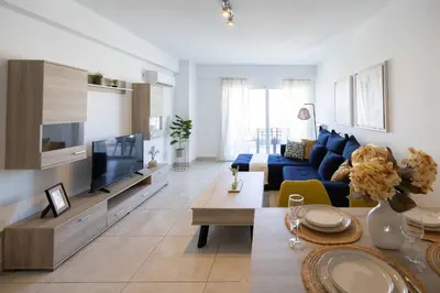 a living room with a blue couch and a tv at Bright 2BR flat with city view in Piraeus Η6 in Piraeus