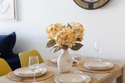 a table with plates and a vase with flowers in it at Bright 2BR flat with city view in Piraeus Η6 in Piraeus