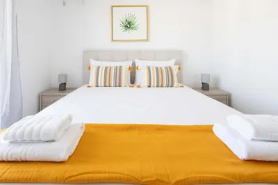 a bedroom with a large white bed with yellow blanket at Bright 2BR flat with city view in Piraeus Η6 in Piraeus