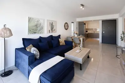 a living room with a blue couch and a kitchen at Bright 2BR flat with city view in Piraeus Η6 in Piraeus