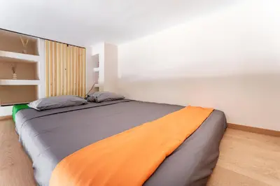 a bedroom with a large bed with an orange blanket at A1 Porto Living in Piraeus