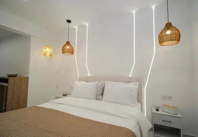a bedroom with a bed with white walls and pendant lights at Athens City-Break Studios- near Acropolis in Athens