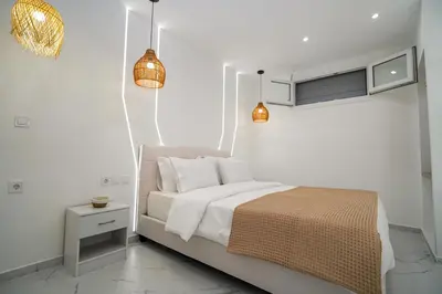 a white bedroom with a bed with white sheets and pillows at Athens City-Break Studios- near Acropolis in Athens