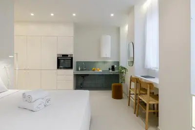 a white room with a bed and a kitchen at Ivory - Studio in Thisseio in Athens