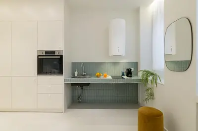 a white kitchen with a sink and a mirror at Ivory - Studio in Thisseio in Athens